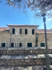 a stone building with shutters and a lamp post