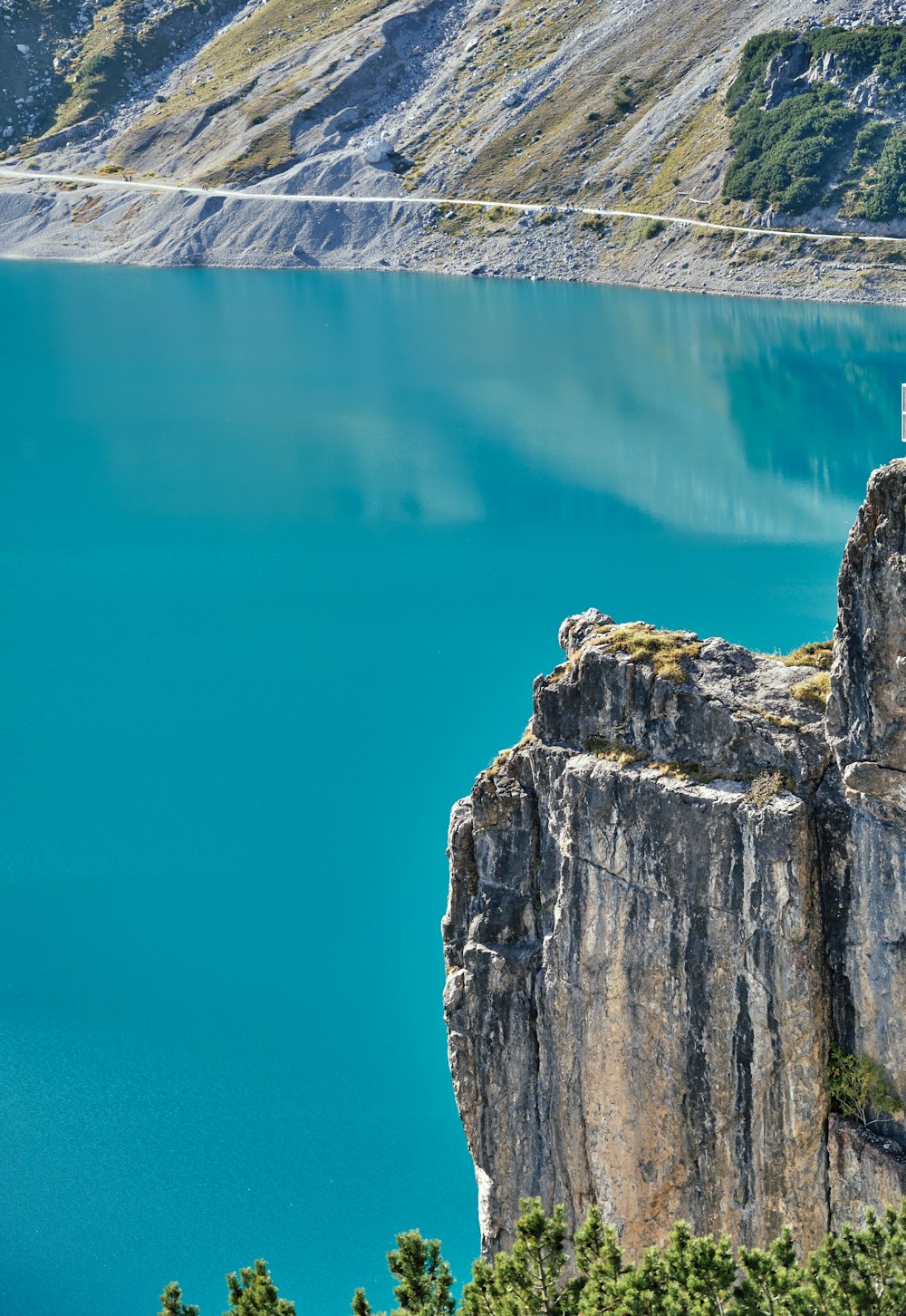 a man standing on top of a cliff next to a lake