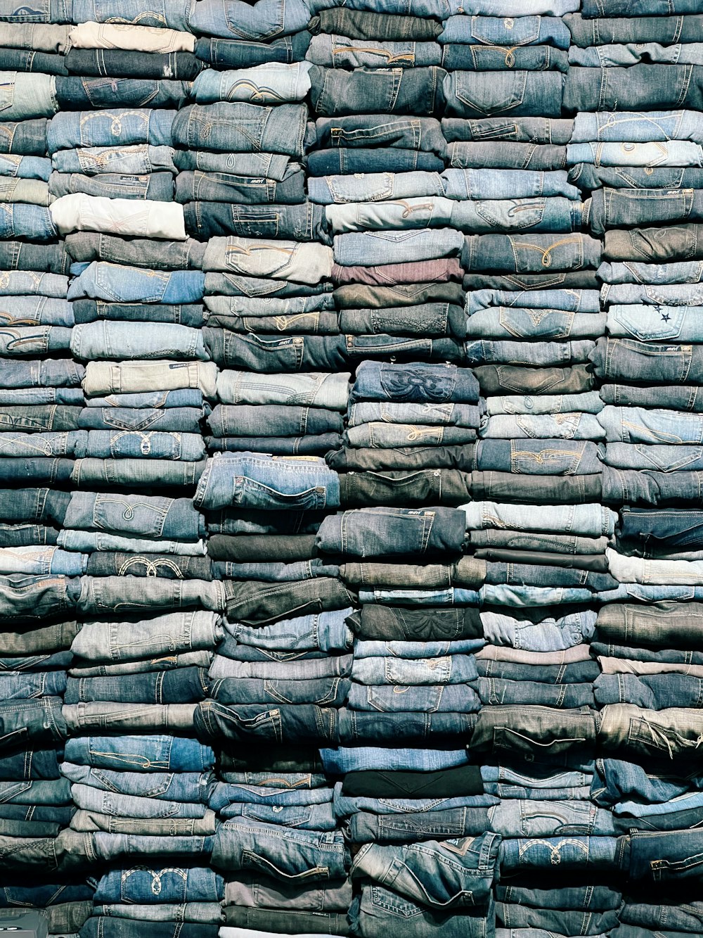 a pile of blue jeans stacked on top of each other