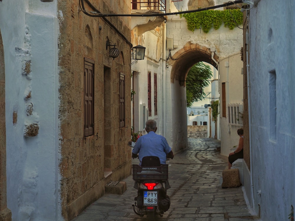 a man riding a motorcycle down a narrow alley way