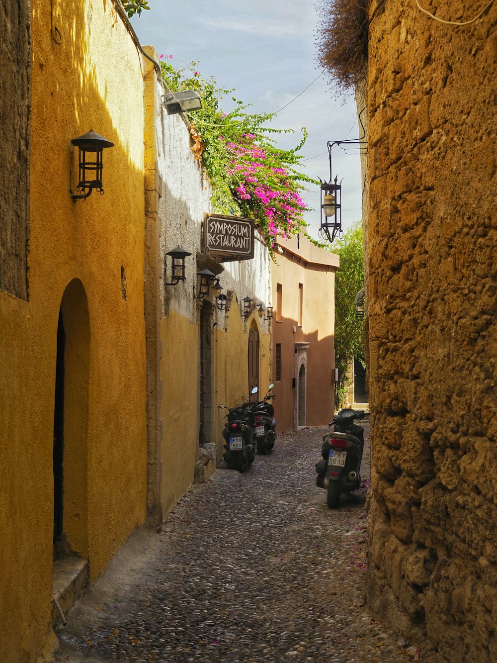 a narrow cobblestone street lined with parked mopeds