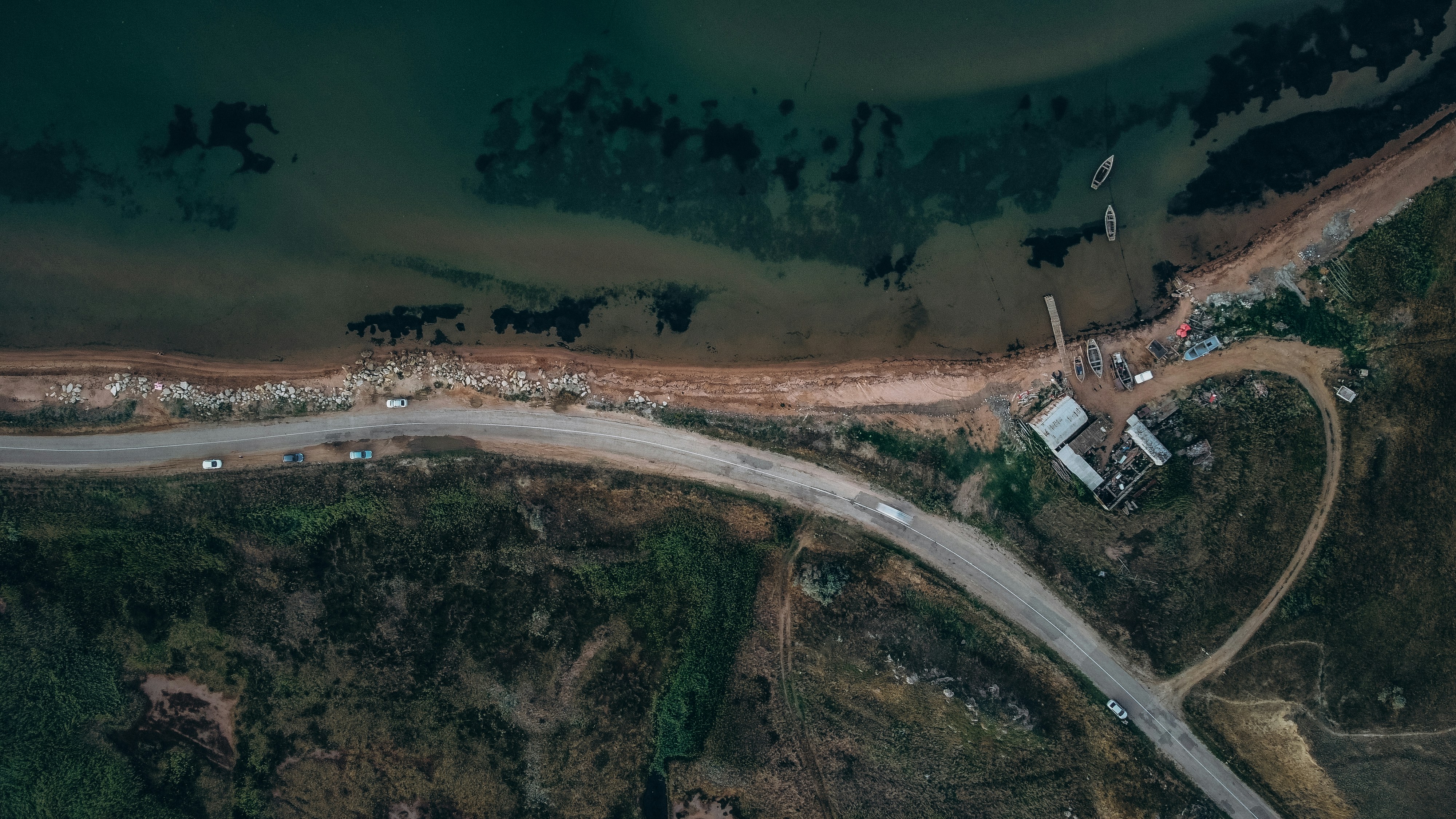 an aerial view of a road near a body of water