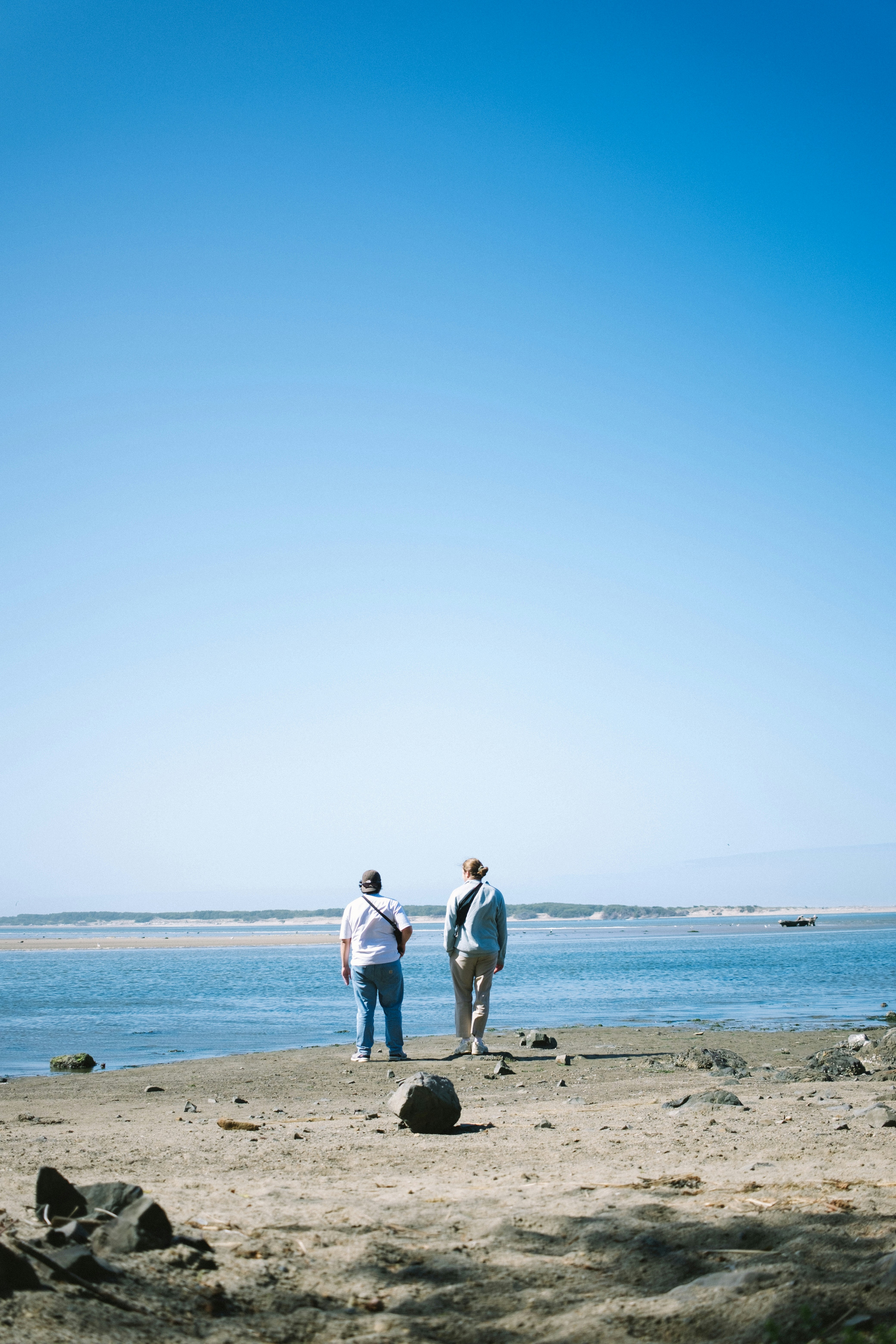 a couple of people standing on top of a sandy beach