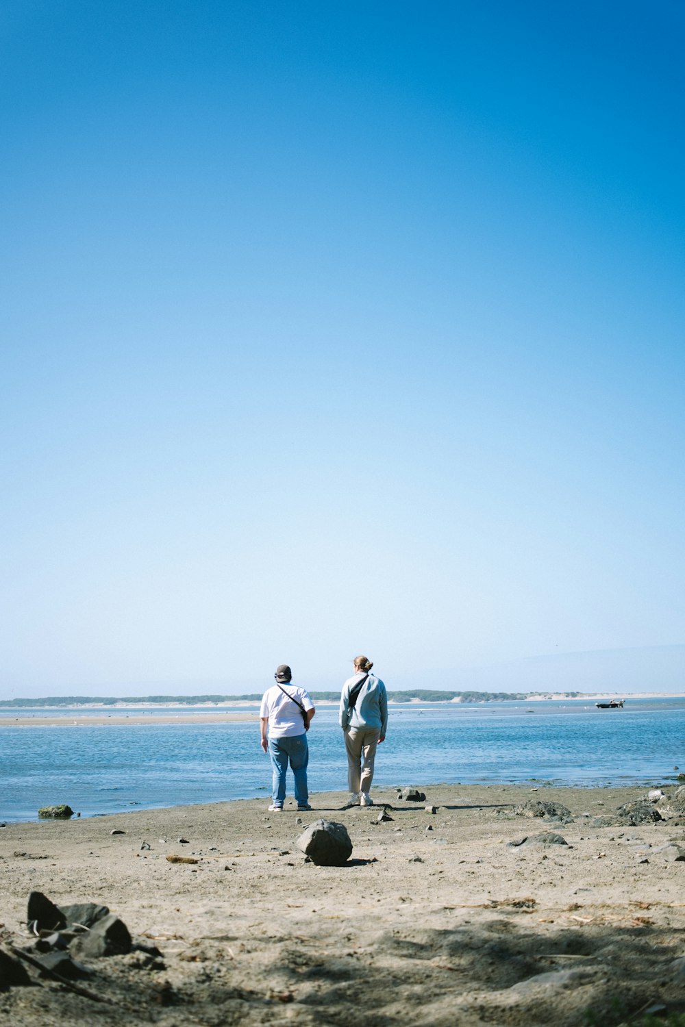 um casal de pessoas em pé em cima de uma praia de areia