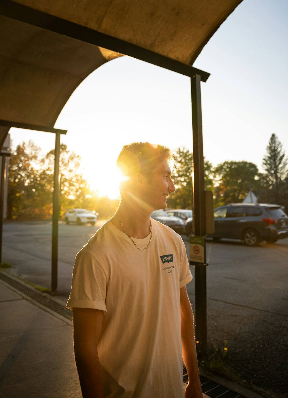 a man standing under a covered area next to a parking lot