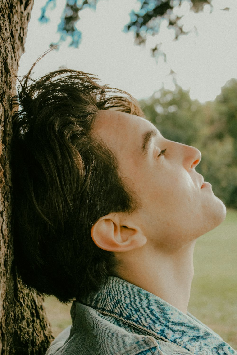 a man leaning against a tree in a park