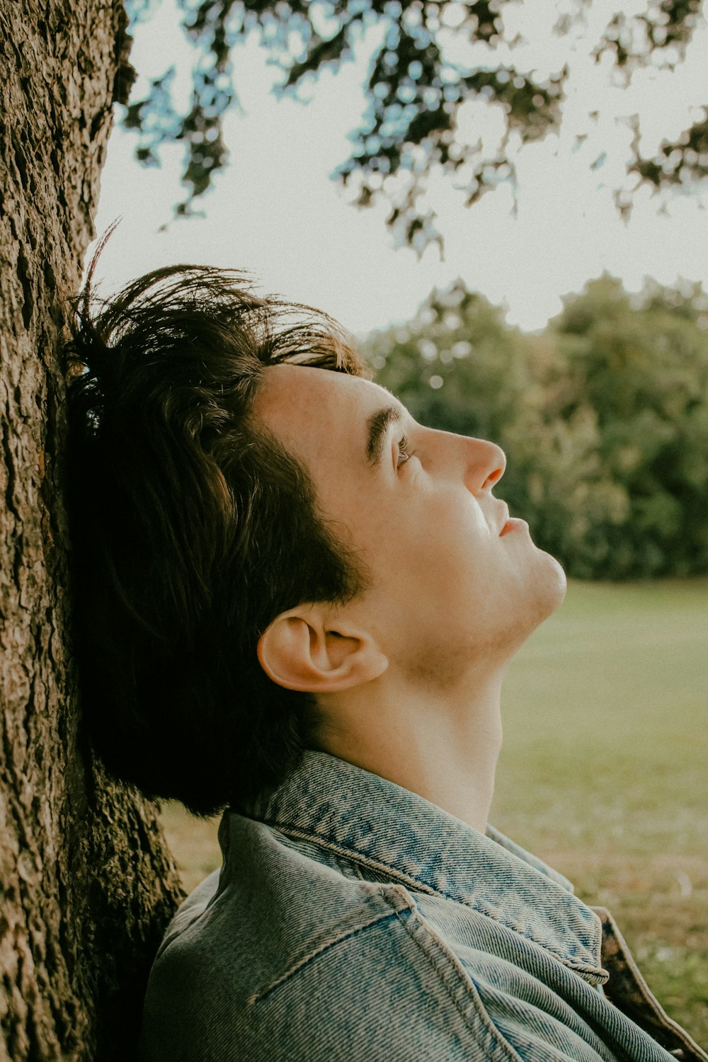 a man leaning against a tree in a park