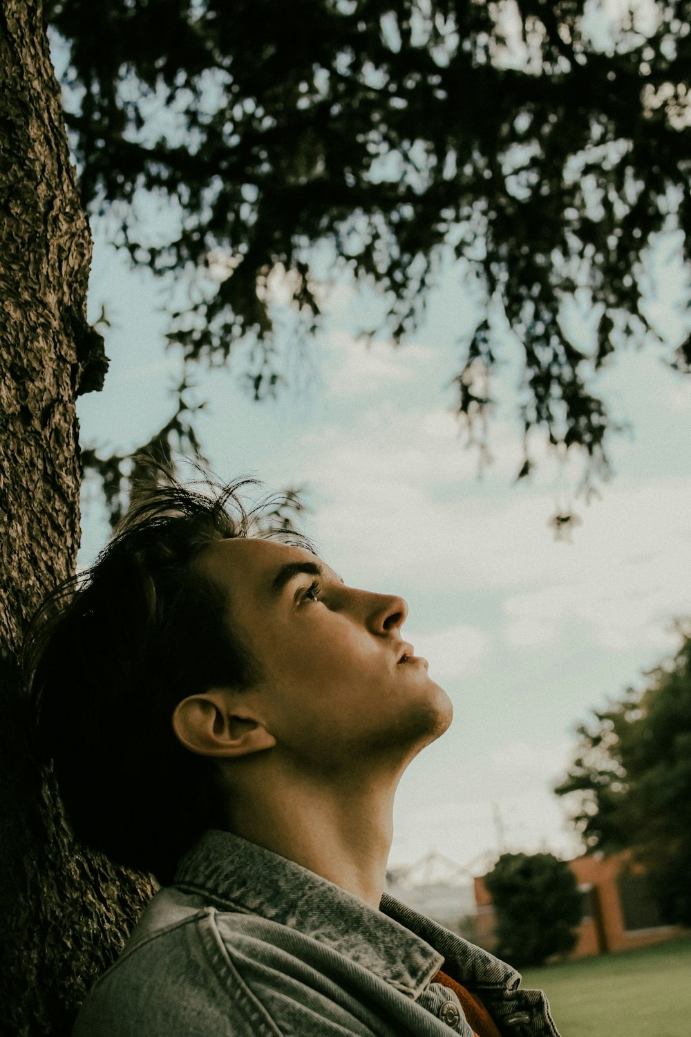 a man leaning against a tree looking up at the sky