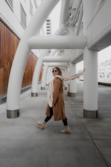 a woman walking down a sidewalk next to tall white pillars