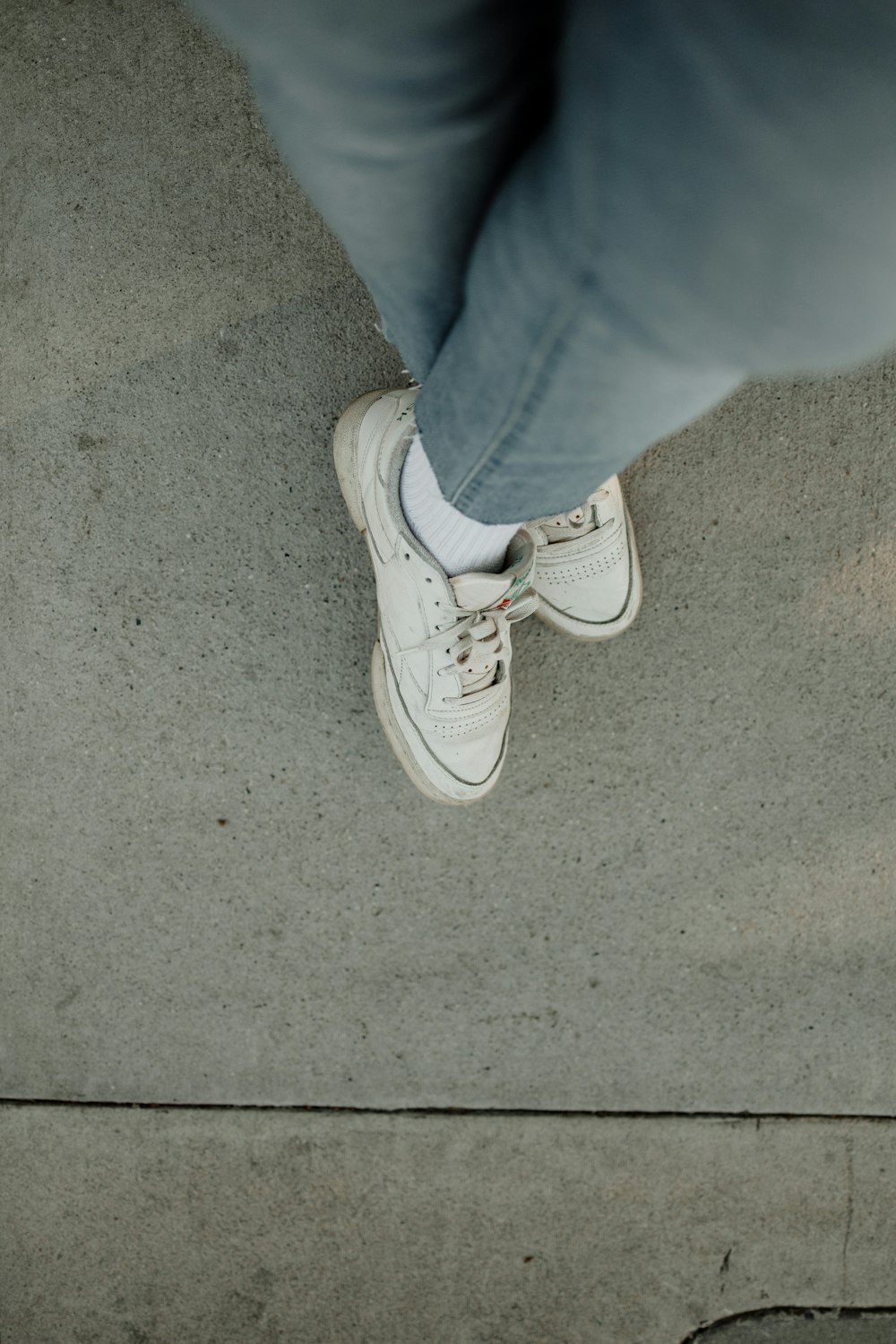 a person standing on a sidewalk with white shoes