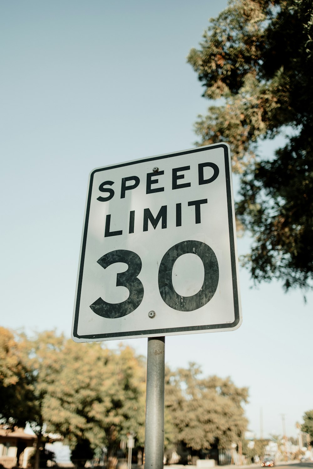 a speed limit sign sitting on the side of a road