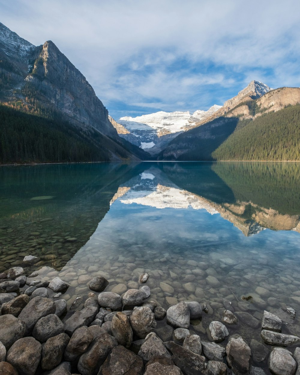 a lake surrounded by mountains with rocks in the foreground