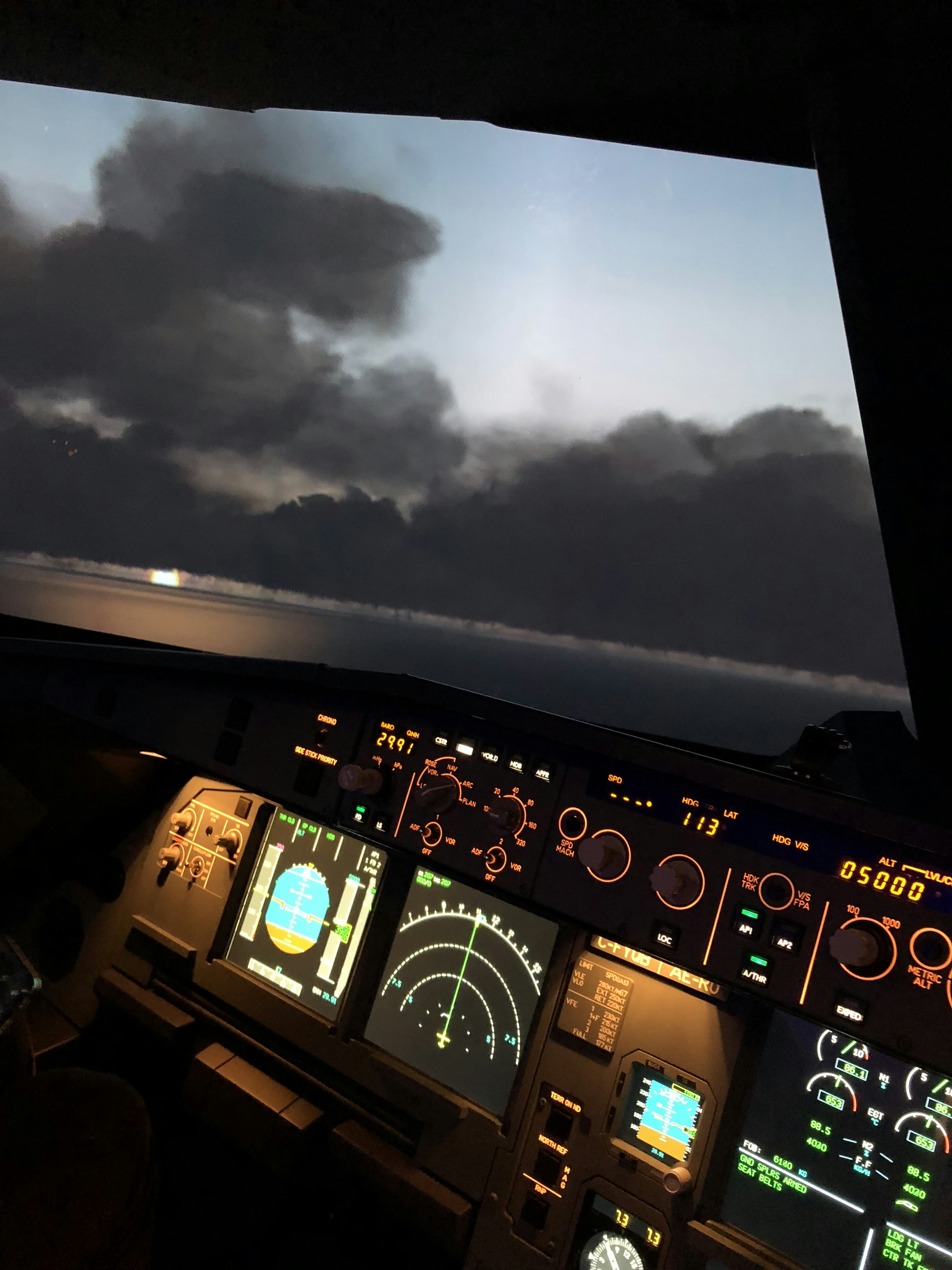 Commercial aircraft cockpit at golden hour, warm instrument glow, dark professional flight deck