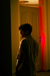 A thoughtful person reflecting in a dimly lit room with yellow and white highlights.