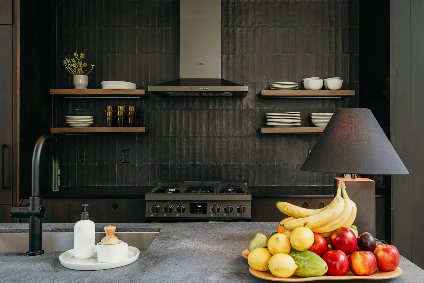 Bowl of fruit on a stone counter in a moody black kitchen