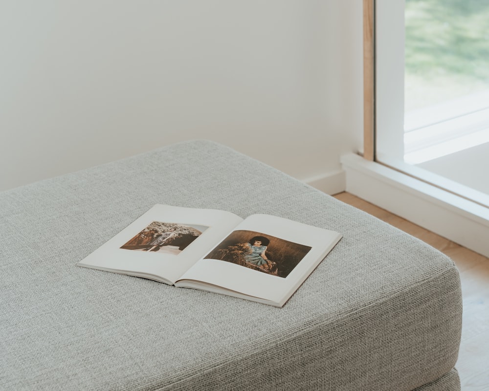 an open book sitting on top of a gray ottoman
