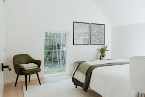 Bedroom with soft linens and a view of the surrounding greenery.