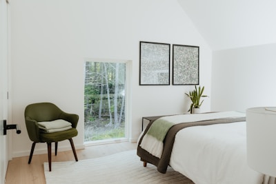 A minimalist bedroom with a large leafy plant beside the bed adding freshness.