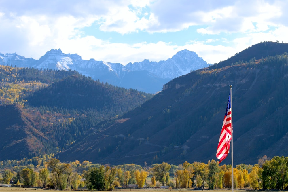 an american flag in front of a mountain range