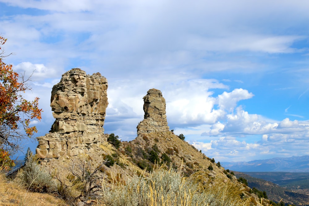 um par de grandes rochas sentadas no topo de uma colina