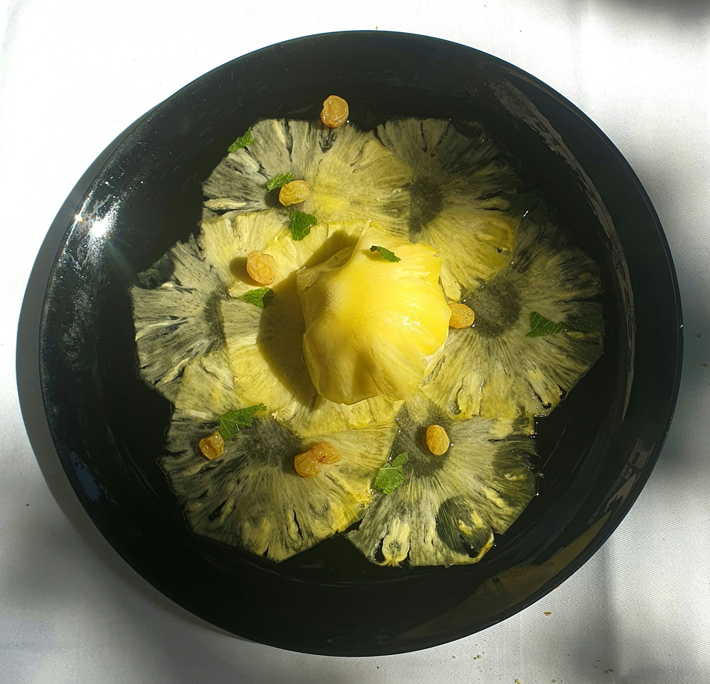 Fresh pineapple rings sliced and arranged on white plate with mint garnish