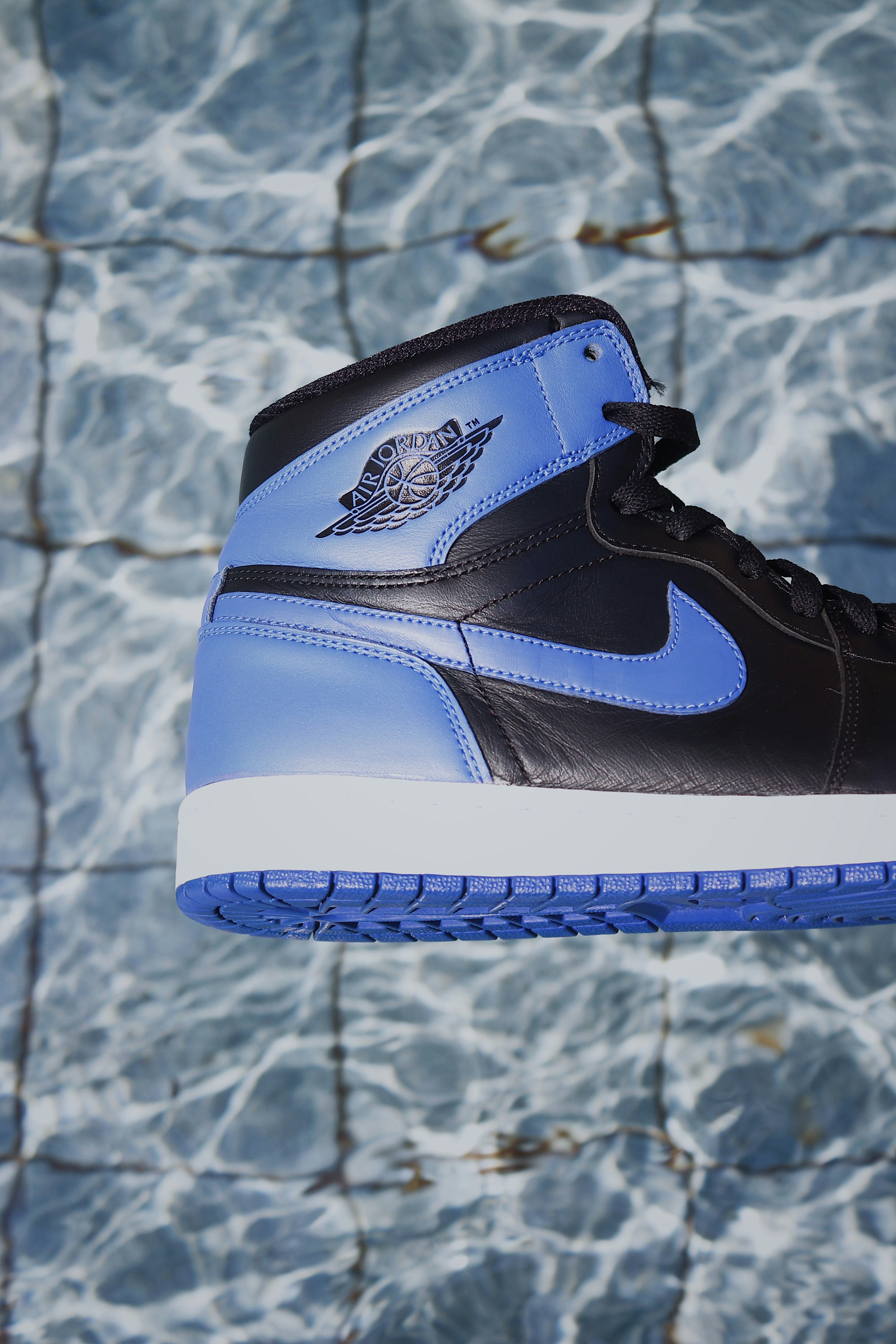 a person holding a pair of black and blue sneakers