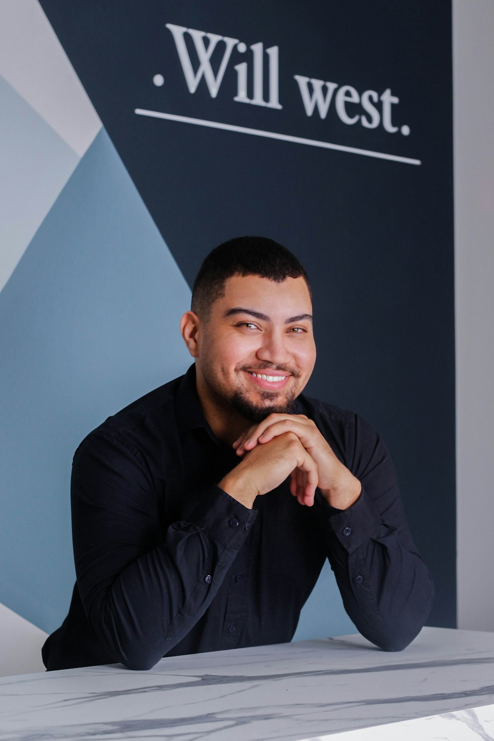 a man sitting at a table in front of a sign