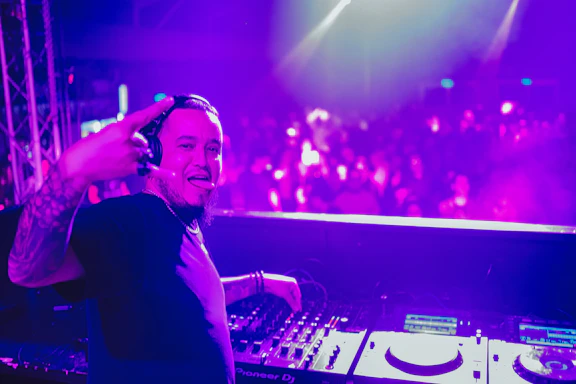 DJ mixing on a colorful stage with vibrant lights and happy crowd.