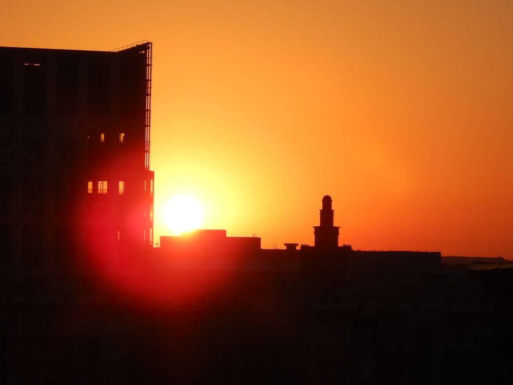 the sun is setting behind a tall building