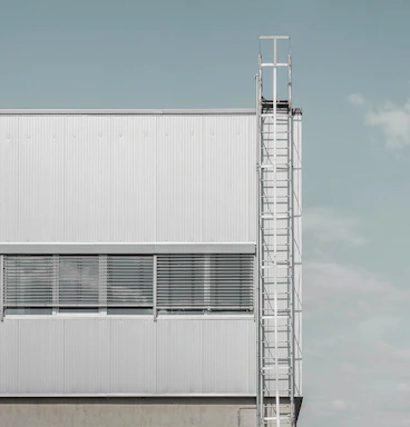 Exterior view of a factory building with steel grey panels and orange accents.