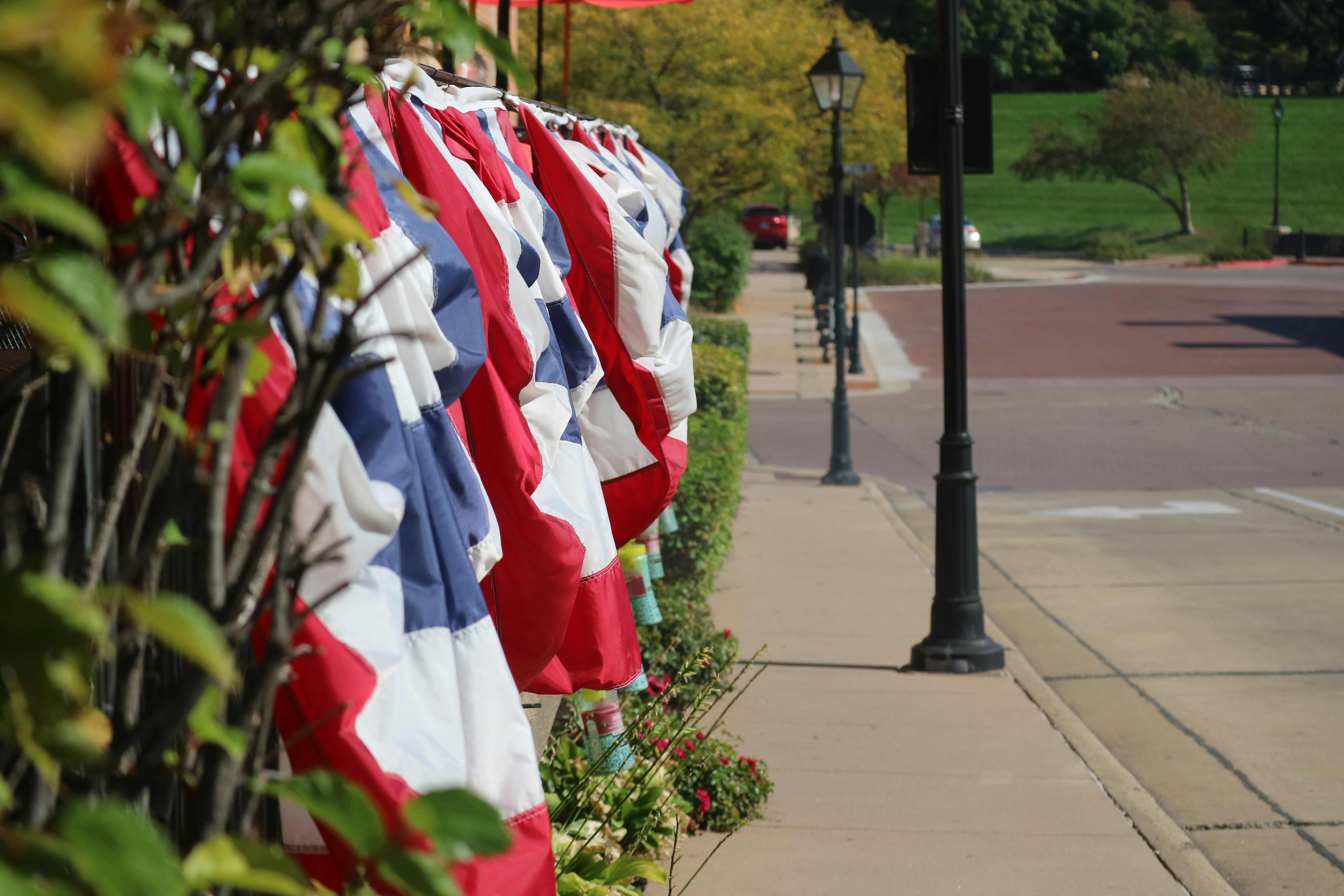 a row of red, white and blue flags on a sidewalk, 