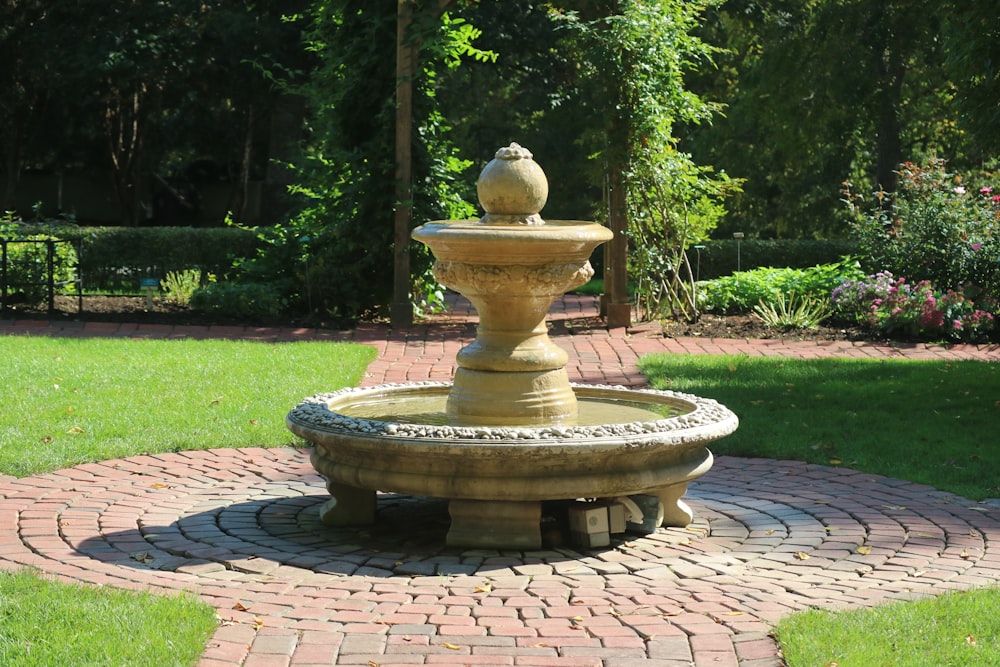 a stone water fountain sitting on top of a brick walkway