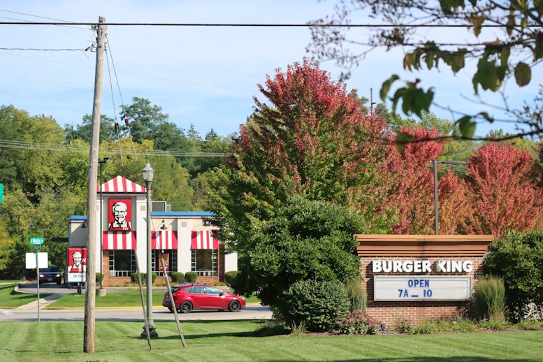 a red car is parked in front of a burger king