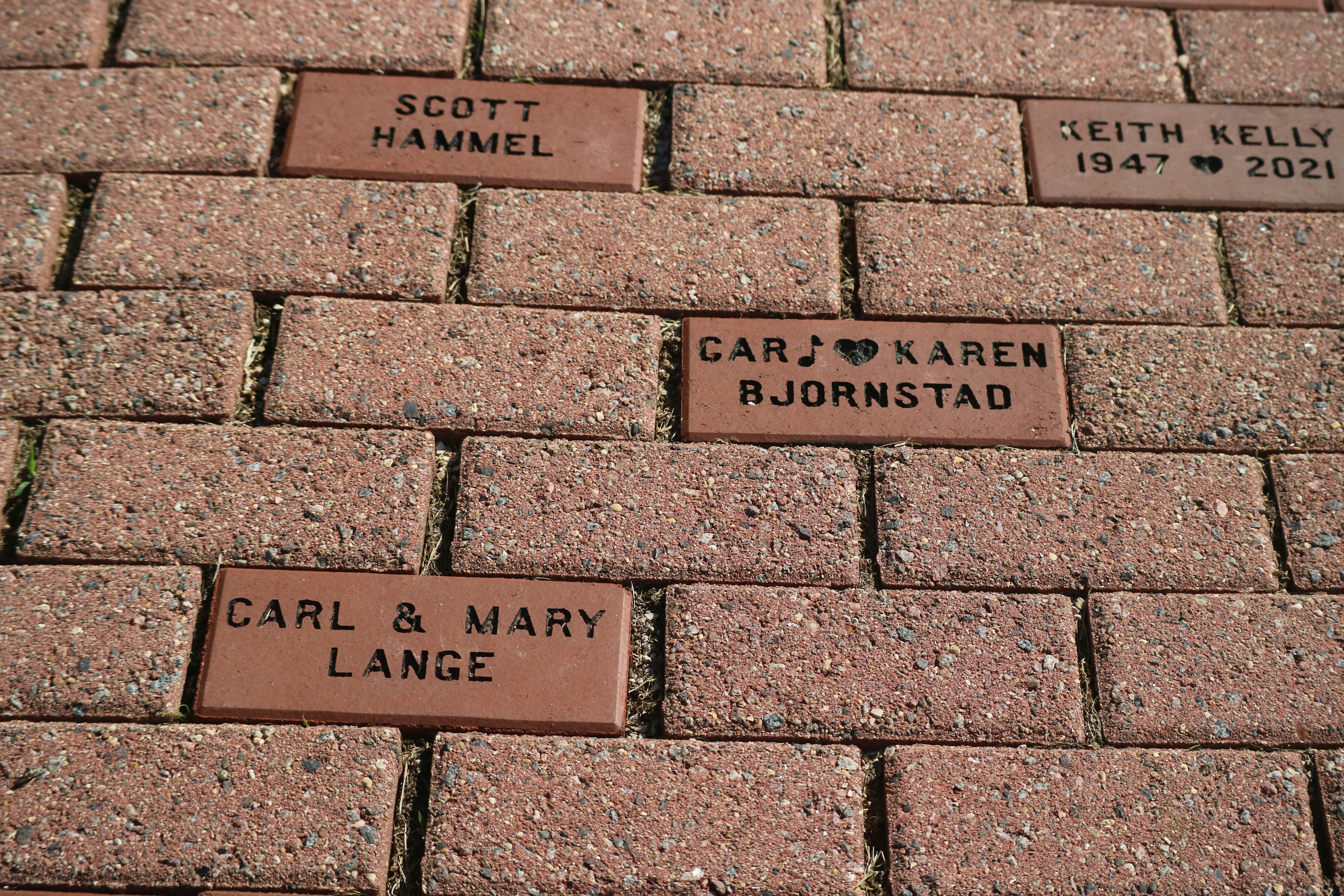 a brick walkway with names and hearts on it