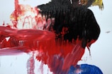 Close-up of a vibrant abstract painting with dramatic red and black strokes.