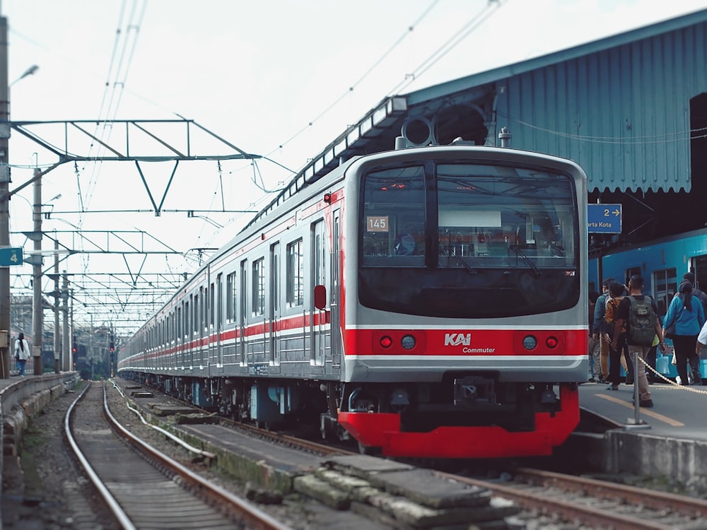 a red and silver train pulling into a train station