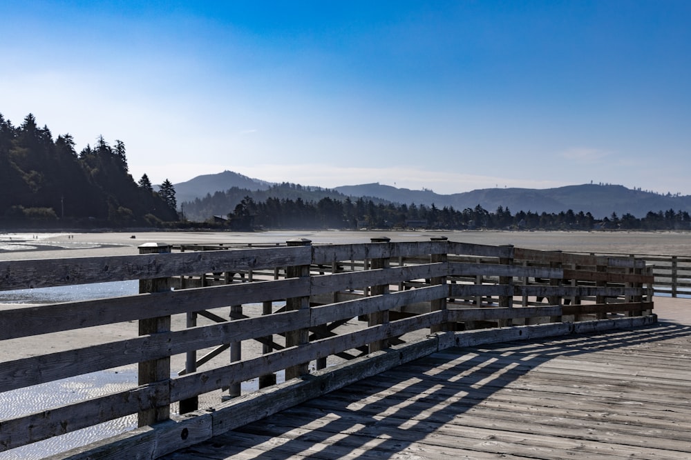 a wooden pier on a beach with mountains in the background