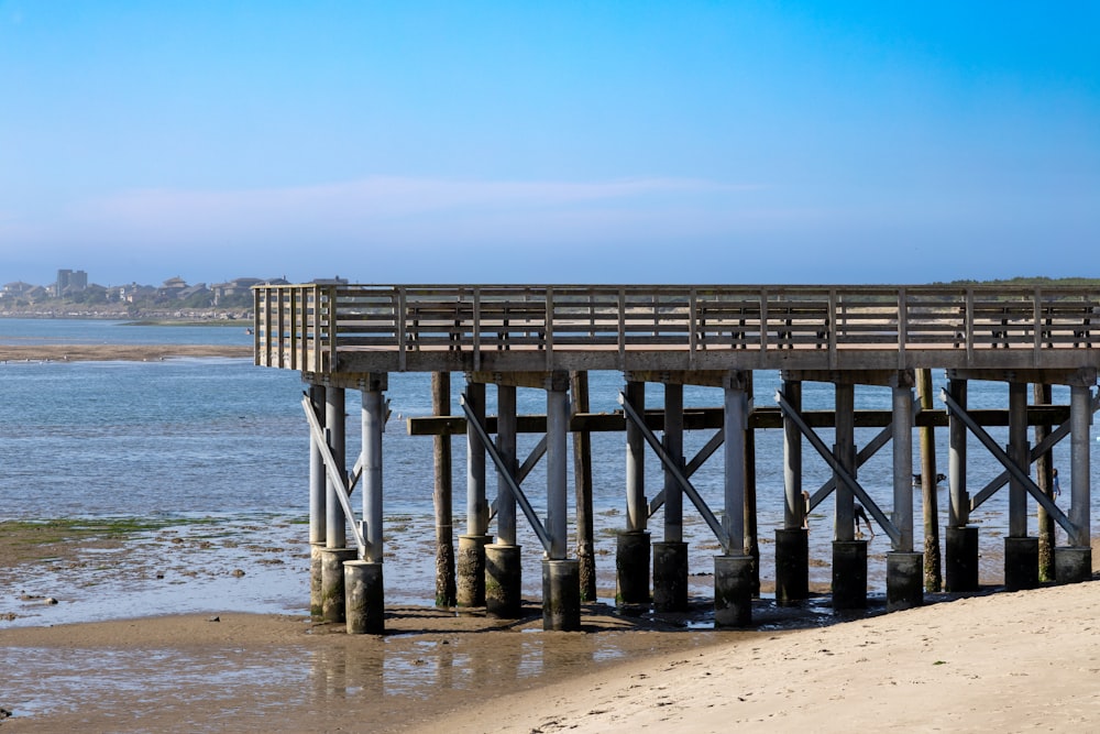 a pier on a beach with a body of water in the background