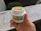 A hand holding a small white container labeled LivRelief Infused, featuring THC and CBD details. The label has a green background with a red THC symbol. The container is open, displaying a cream inside. The setting appears to be outdoors with a blurred background.