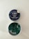 A tin of CBD gummies labeled 'Blueberry Dream' with an open lid revealing square-shaped green gummies inside. The label indicates it contains 25mg of CBD and is THC free. The tin has a dark blue label with images of blueberries and leaves.