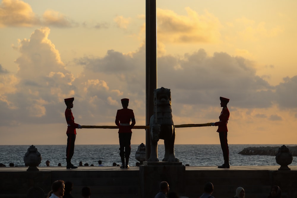 a group of people standing on top of a pier next to the ocean