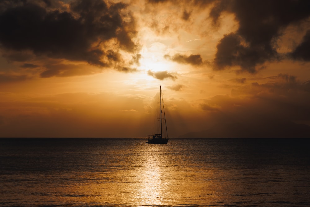 a sailboat in the ocean at sunset