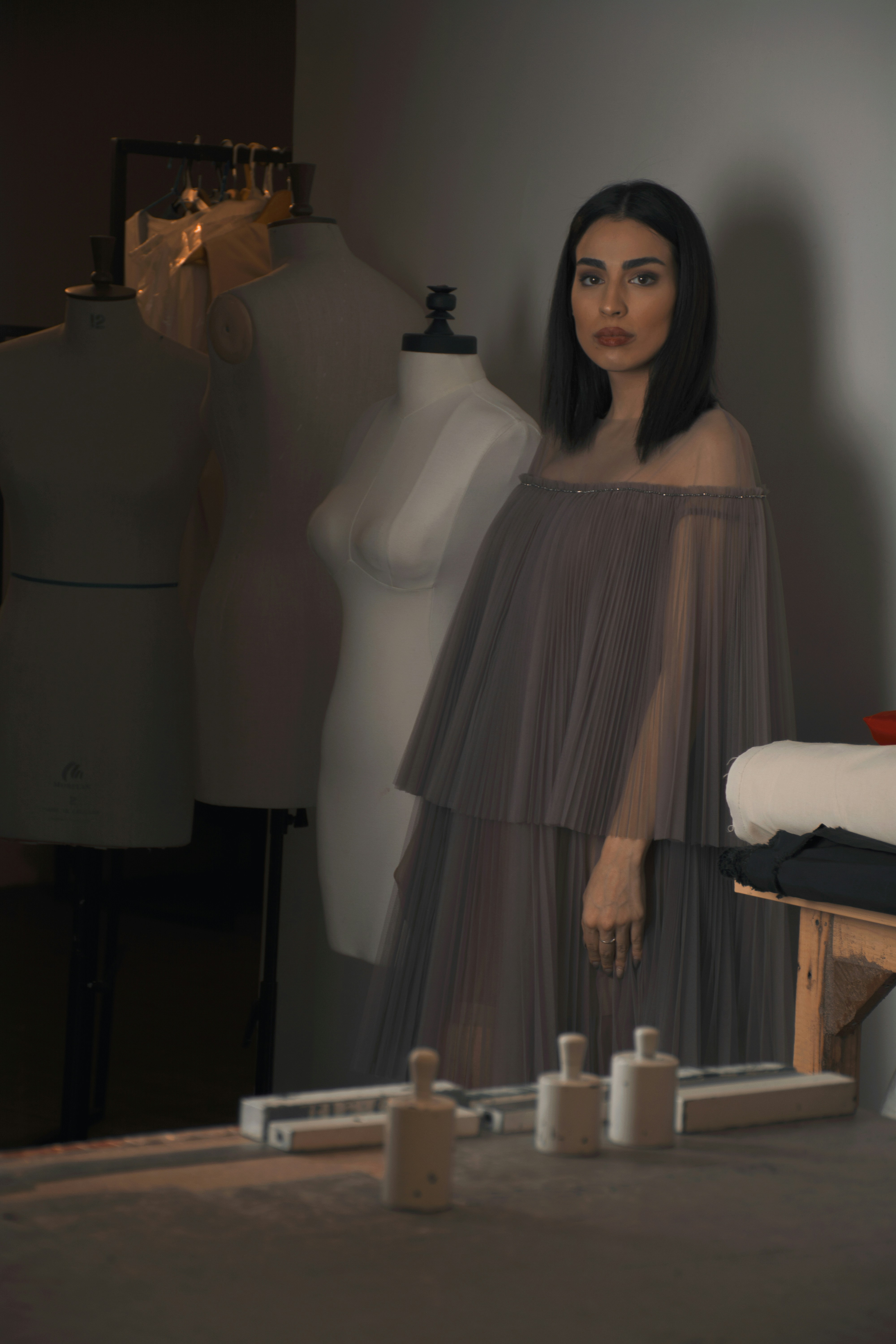 a woman standing next to a dress on a mannequin