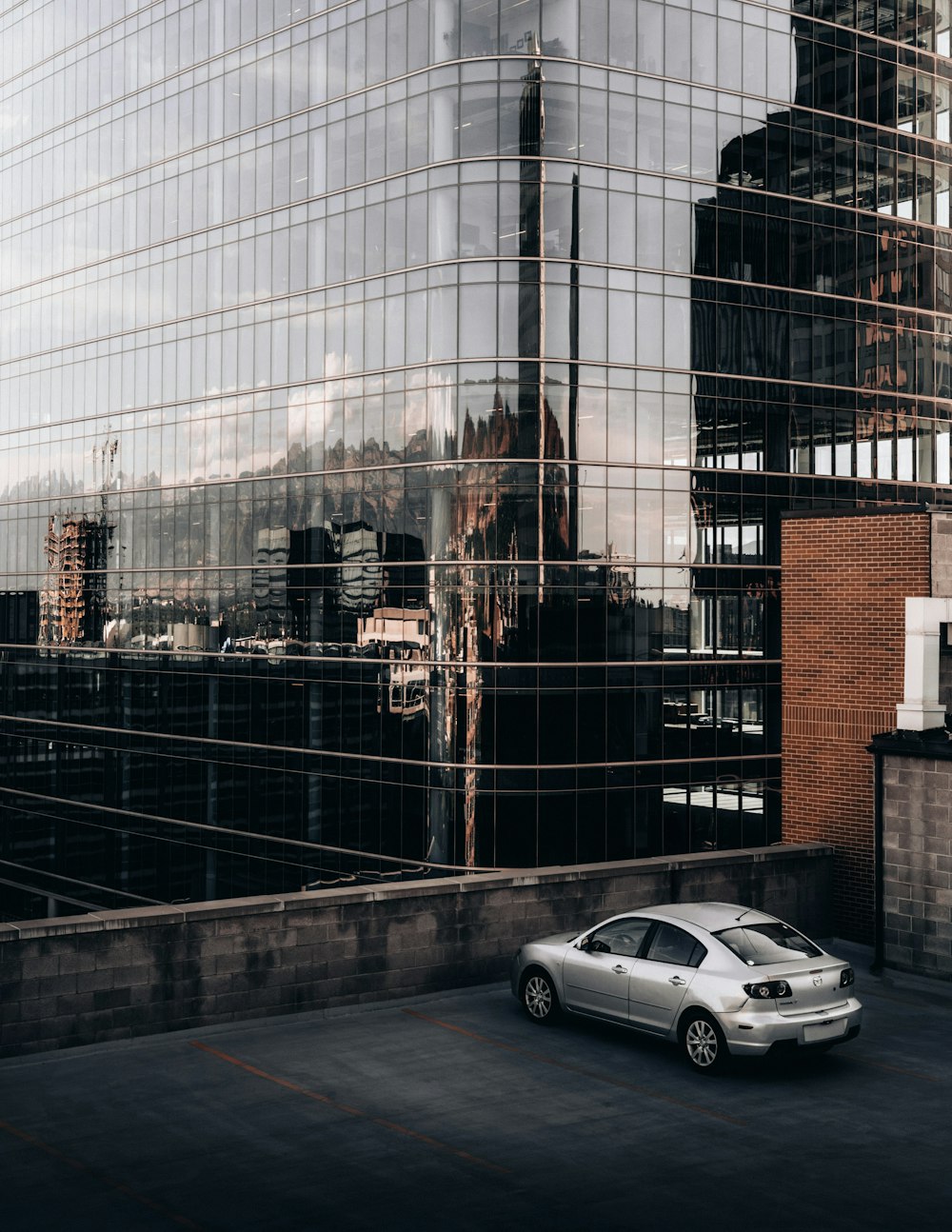 a silver car parked in front of a tall building