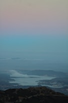 A serene landscape photo of a misty morning by the lake with soft pastel colors.