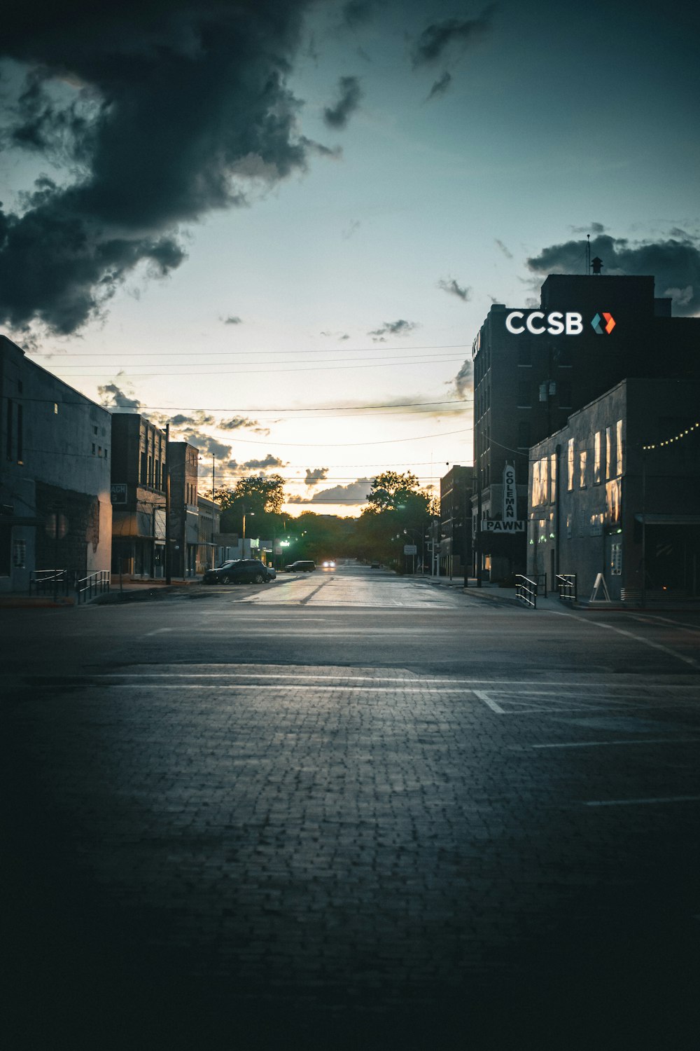 a dark street with buildings and a cloudy sky