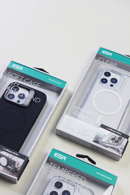 Several ESR brand phone cases in various packaging designs, including a soft case, a clear case, and a tempered glass case, displayed on a light surface.