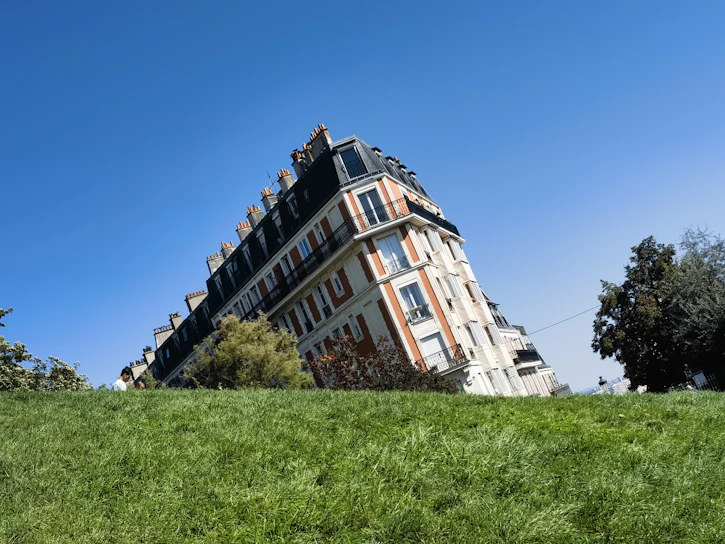 Elegant Parisian hotel facade with lush gardens under a clear blue sky