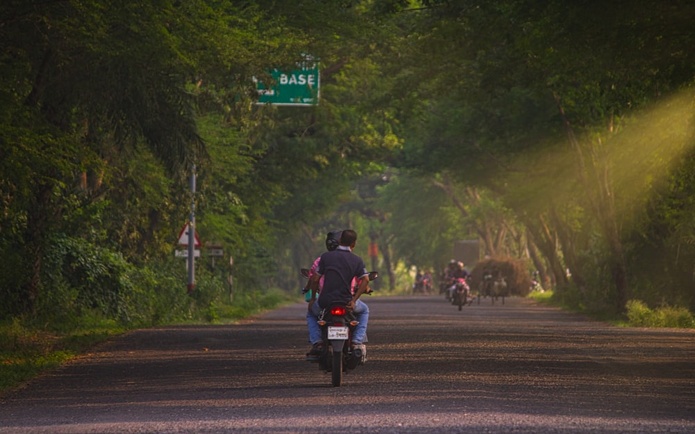 a man riding a motorcycle down a road next to a forest