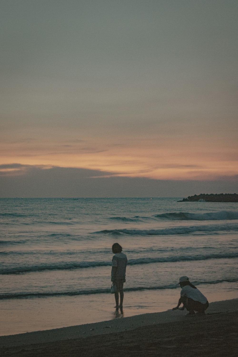 a couple of people standing on top of a beach